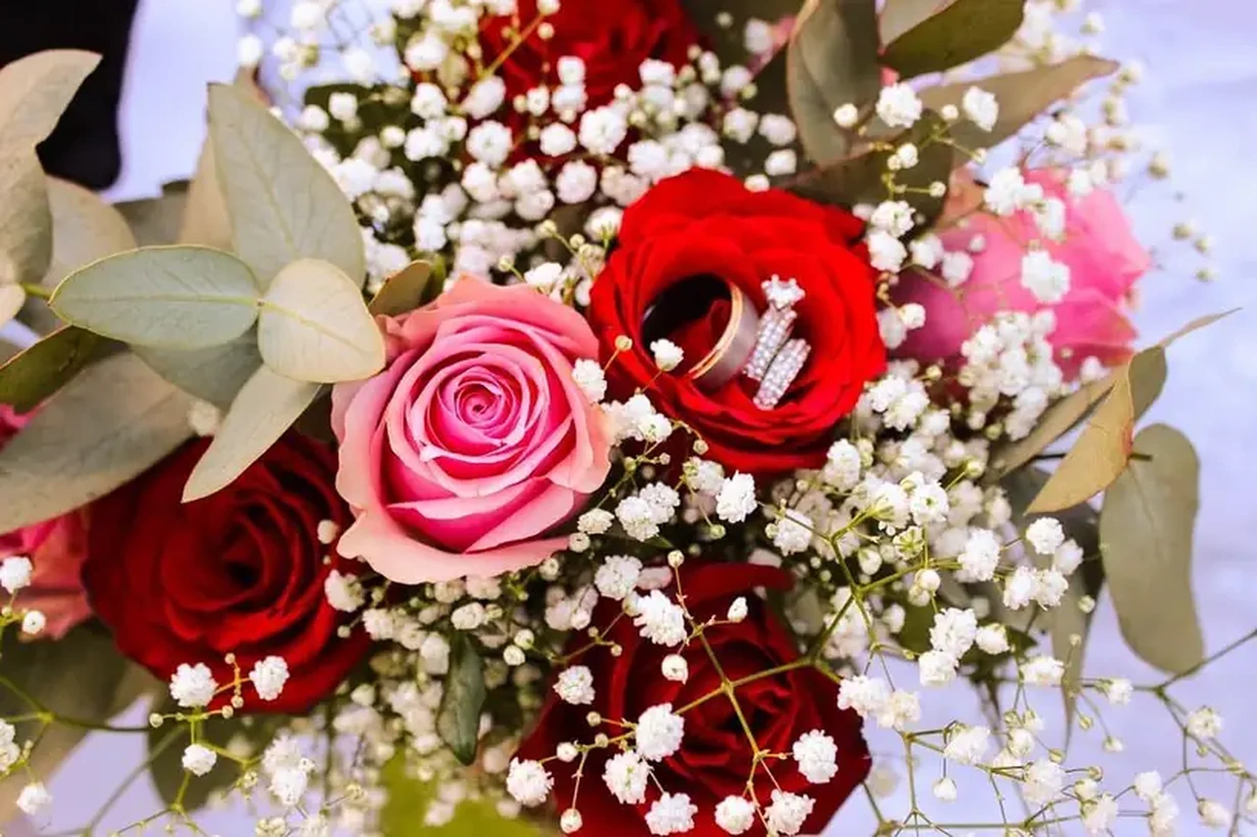 Bouquet of red and pink roses with baby's breath and wedding rings